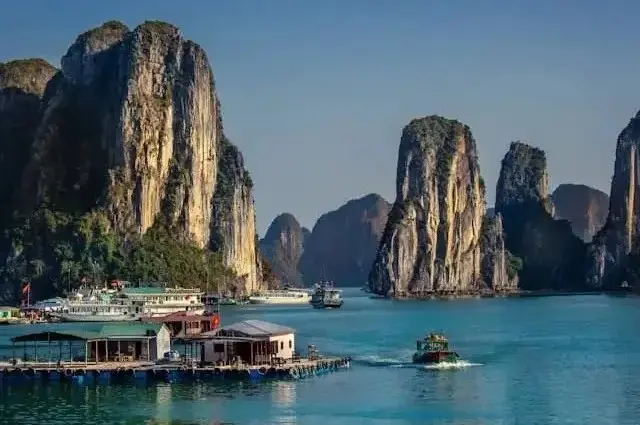 Fishing village and towering cliffs in Halong Bay on a sunny day