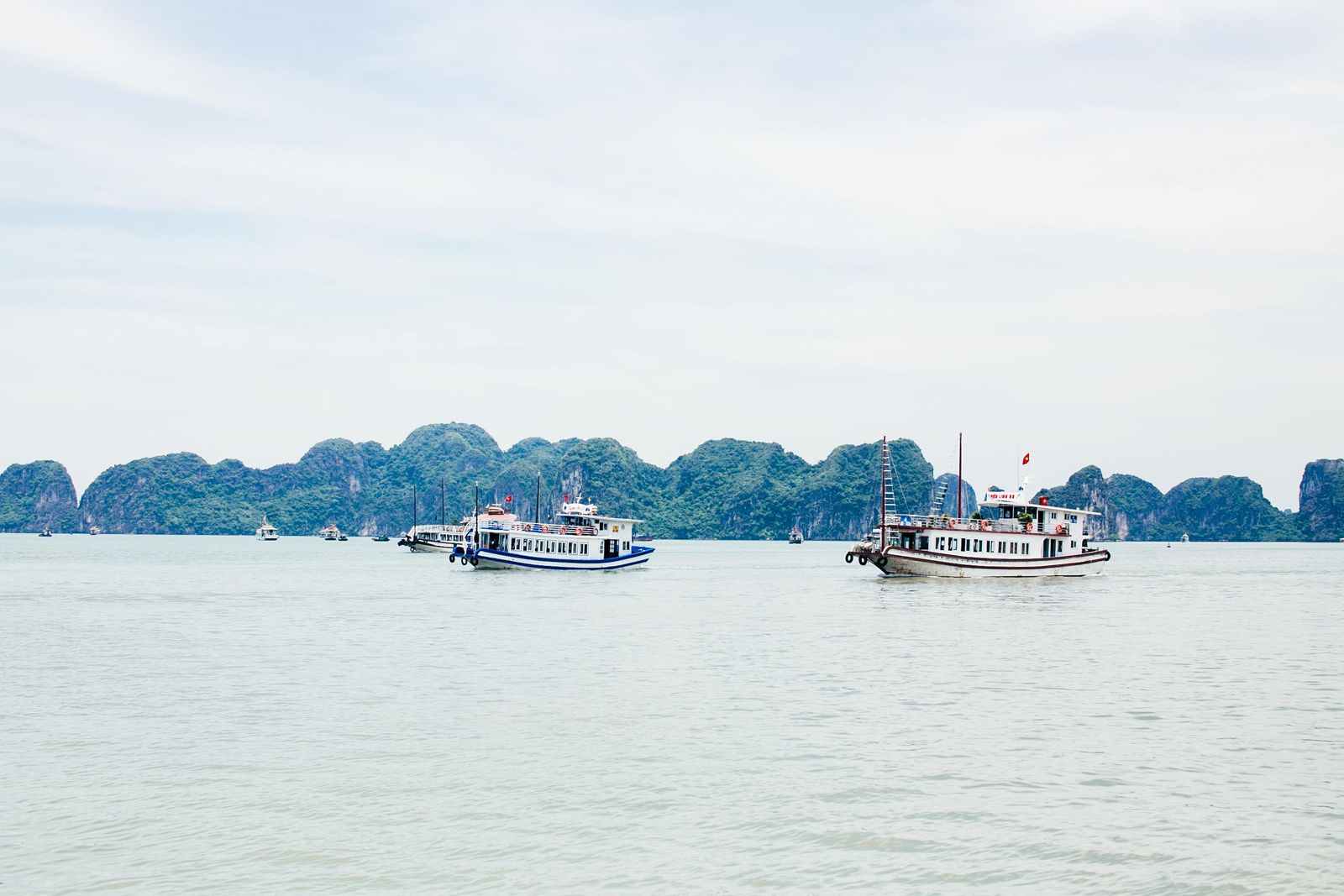 Cruise boat passing limestone karsts on a day route in Halong Bay